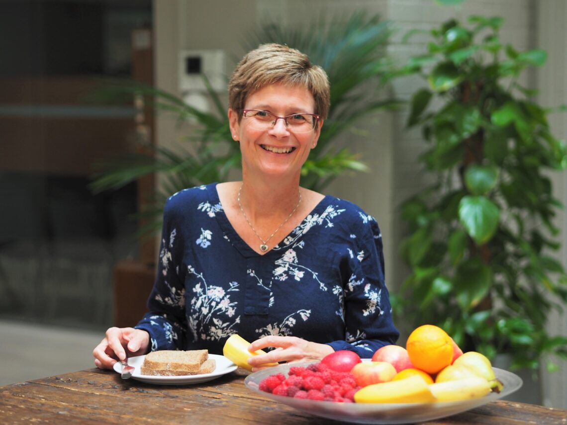 Bildet viser Mona Bjelland fra Kreftforeningen som står bak et bord med mat på.